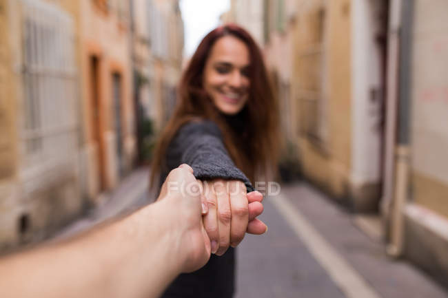 Smiling brunette gesturing follow me on blurred urban background. — Stock Photo