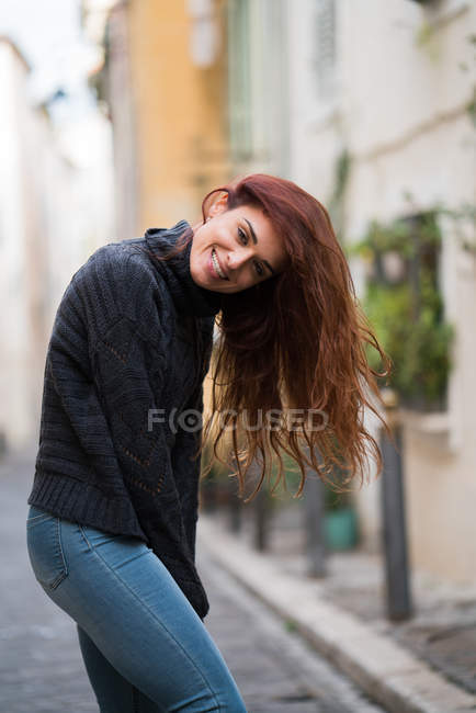 Усміхнена жінка в повсякденному одязі позує на вулиці . — стокове фото