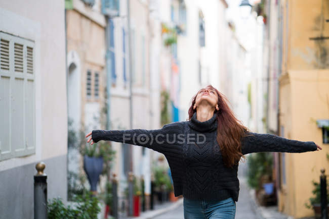 Woman holding hands wide and looking up at street — Stock Photo