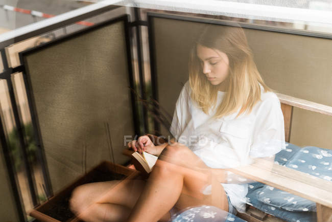Femme lisant un livre sur le balcon — Photo de stock