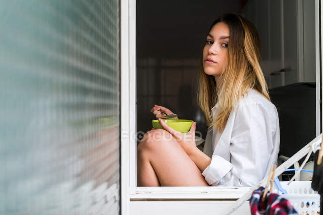 Jeune femme réfléchie prenant le petit déjeuner — Photo de stock