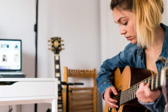 Jeune femme jouant une guitare — Photo de stock