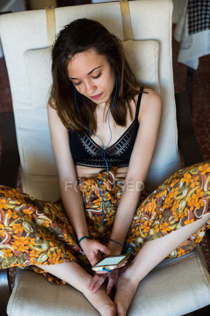 Young girl listening to music in armchair — Stock Photo
