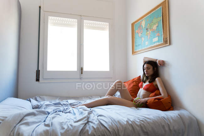Молода дівчина в червоній нижній білизні на ліжку — стокове фото