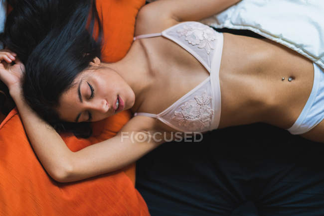 Femmina sdraiata a letto indossando reggiseno — Foto stock