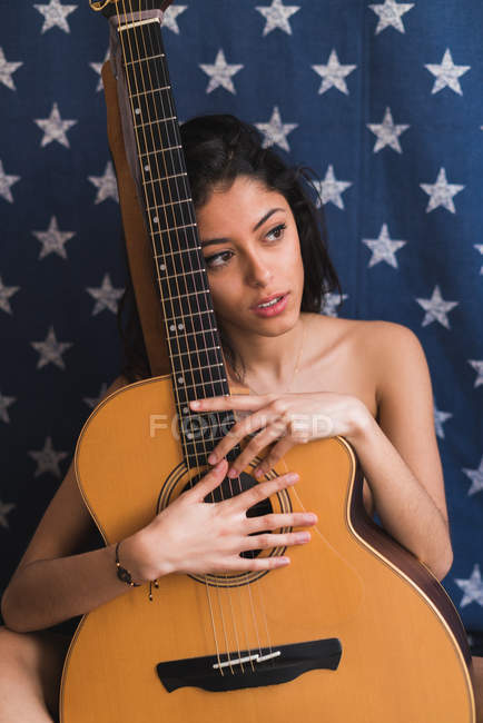 Brünette weiblich sitzend mit gitarre — Stockfoto