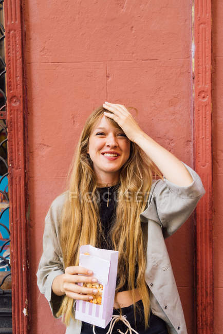 Sonriente chica rubia comiendo palomitas de maíz - foto de stock