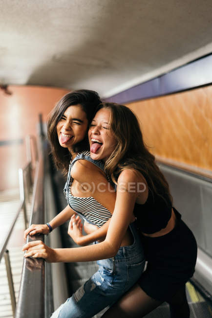 Chicas jóvenes en escaleras mecánicas enloqueciendo - foto de stock