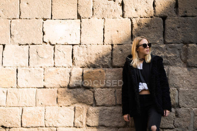 Donna posa contro muro di mattoni — Foto stock