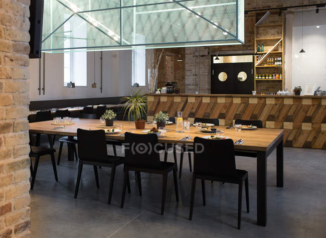 Innenaufnahme einer leeren Cafeteria mit großem Tisch umgeben von Stühlen. — Stockfoto