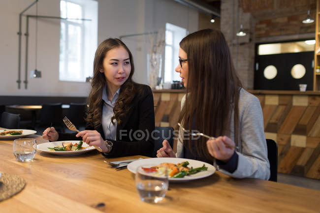 Two female colleagues talking while dinner — Stock Photo