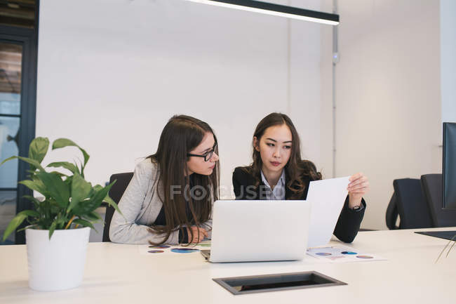 Duas colegas trabalhando com papéis e laptop — Fotografia de Stock
