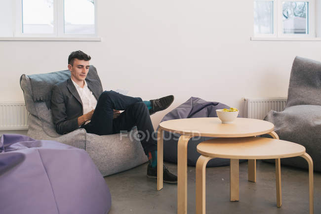 Un hombre reflexivo sentado en la bolsa de frijoles en la oficina - foto de stock