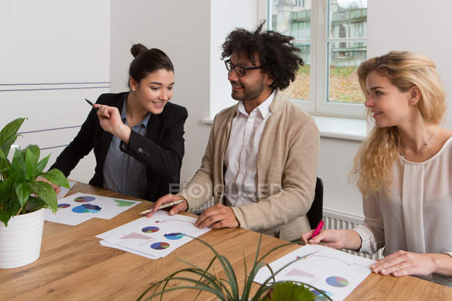 Three coworkers sitting at table and working on diagrams. — Stock Photo