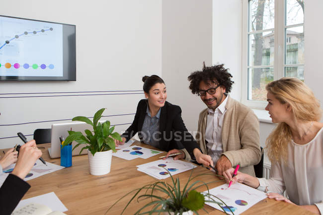 Three colleagues sitting at table and working on diagrams at office — Stock Photo