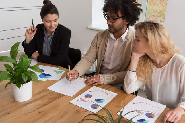 Three colleagues working on diagrams at table in office — Stock Photo