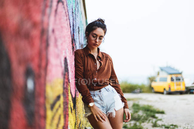 Chica apoyada en la pared de graffiti - foto de stock