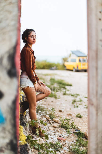 Girl with eyeglasses leaning on graffiti wall — Stock Photo