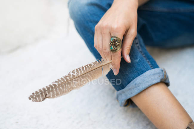 Woman in jeans holding feather — Stock Photo