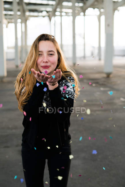Jeune fille soufflant confettis — Photo de stock