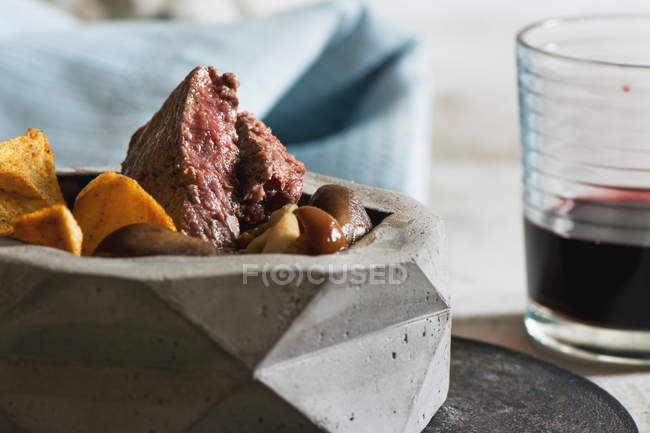 Tenderloin steak with mushrooms and potato fries in stone bowl — Stock Photo