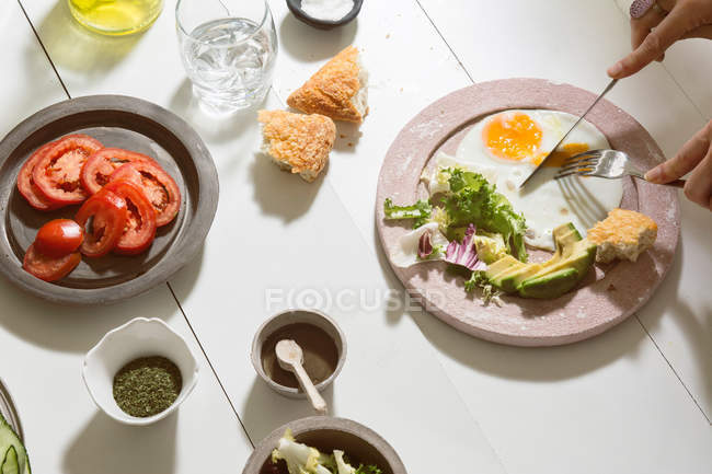 Crop hands cutting fried eggs — Stock Photo