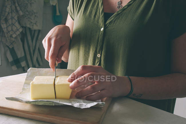 Woman cutting butter — Stock Photo