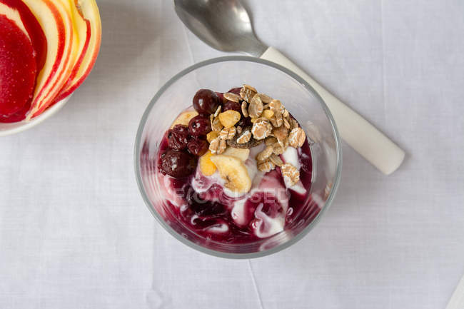Direttamente sopra vista di vetro con yogurt con marmellata e muesli sul tavolo — Foto stock