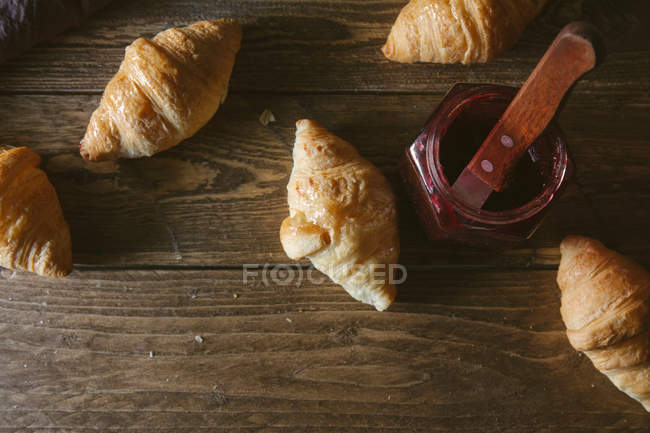 Croisants mit Marmeladenglas auf Holztisch — Stockfoto