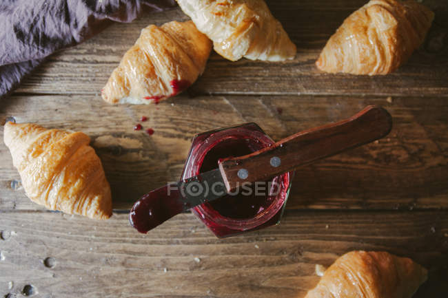 Croisants with jar of jam on wooden table — Stock Photo