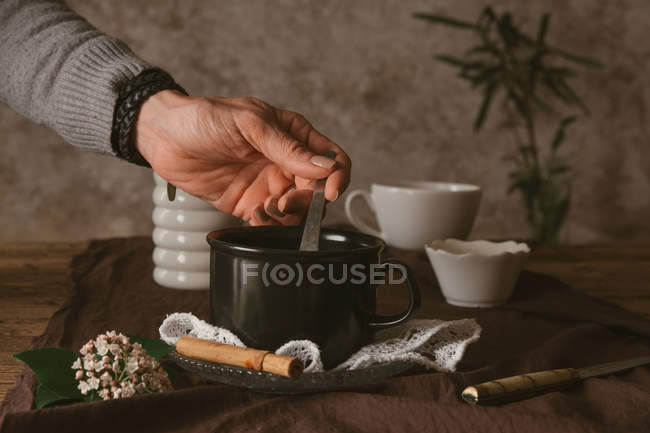 Руки держат ложку в чашке — стоковое фото