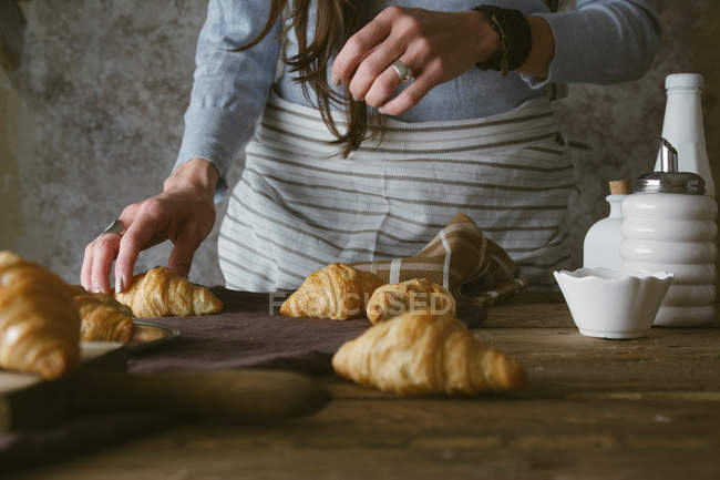 Weibliche Hände nehmen Croissant — Stockfoto