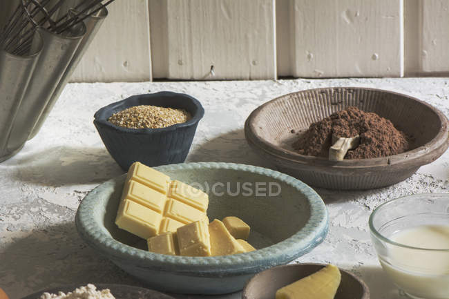 Blue bowl with white chocolate by ingredients on stone table — Stock Photo