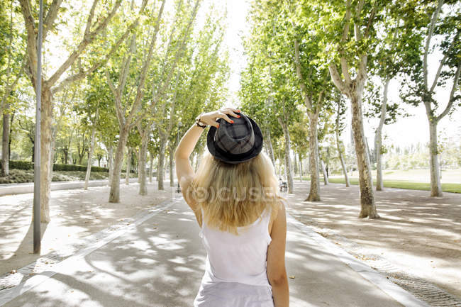 Блондинка тримає капелюх на парковій алеї — стокове фото