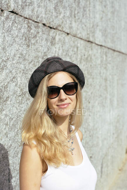 Femme blonde avec chapeau, posant dans un environnement urbain. — Photo de stock