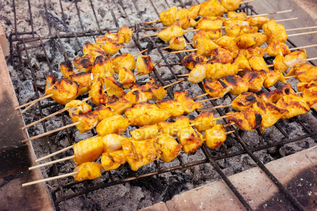 Crusty chicken kebabs on grill grid — Stock Photo
