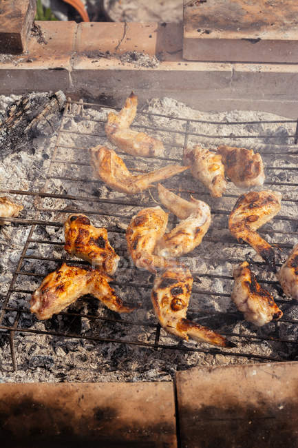 Crusty chicken wings on grill grid — Stock Photo
