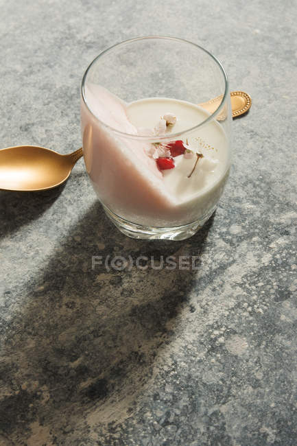 Bicchiere con mousse dolce decorato con fiori e cucchiaio di rame — Foto stock