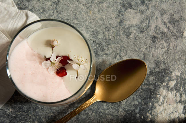 Directly above glass with sweet mousse decorated with flowers and copper spoon — Stock Photo