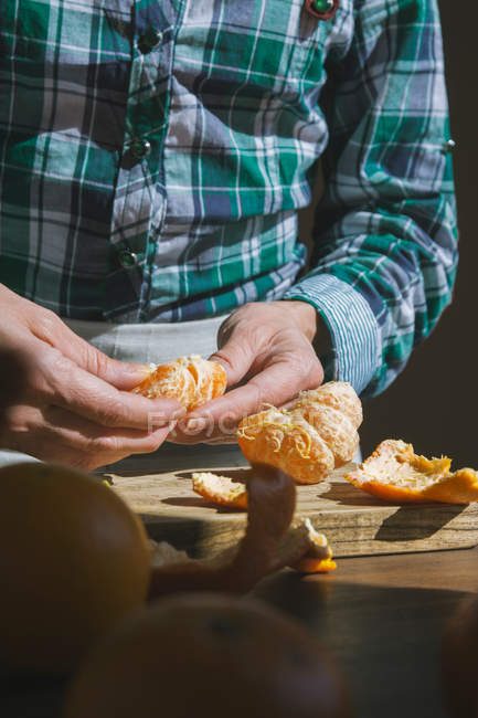 Mulher mão descascamento maduro doce tangerina — Fotografia de Stock