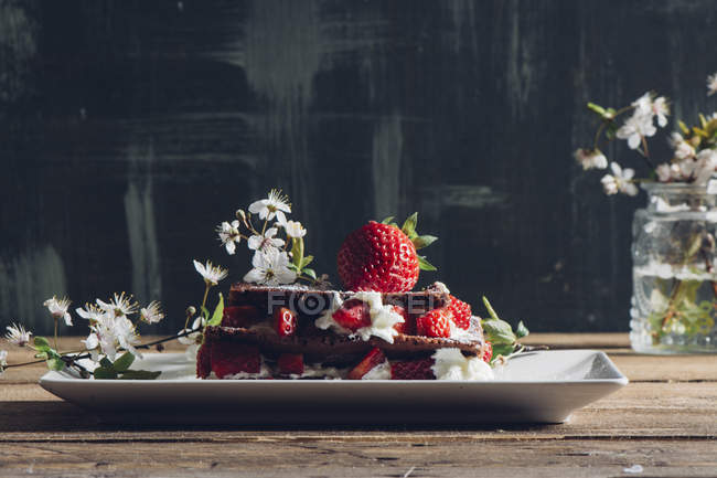 Bodegón de tarta de fresa casera y ramitas florecientes en la mesa rural - foto de stock