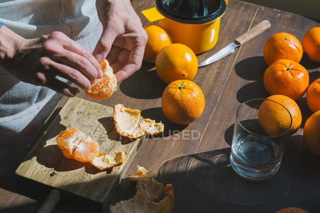 Woman hand peeling ripe sweet tangerine — Stock Photo