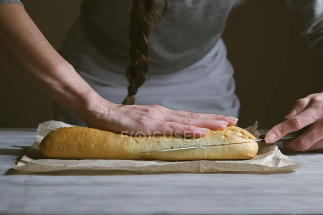 Couper les mains féminines en tranches panini avec couteau — Photo de stock