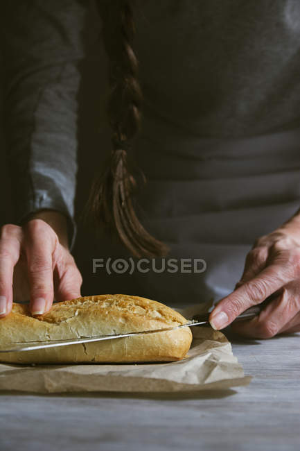 Sección media de la mujer rebanando panini con cuchillo - foto de stock