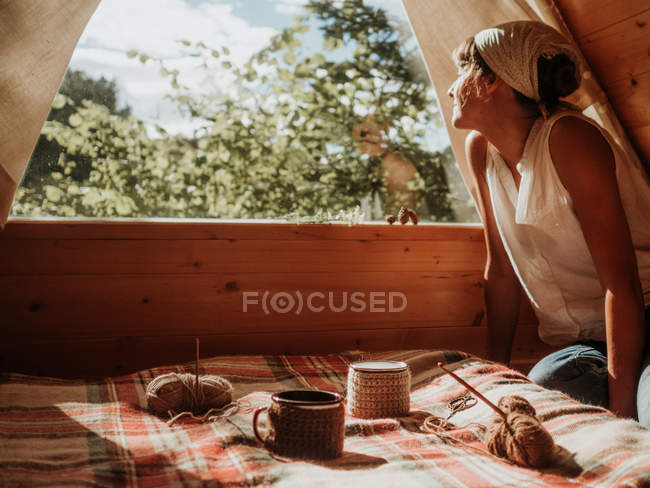 Женщина на деревянном доме наслаждается солнцем — стоковое фото