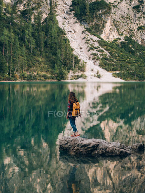 Donna con zaino su pietra nel lago — Foto stock