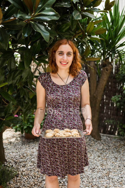 Mujer sonriente sosteniendo galletas caseras - foto de stock