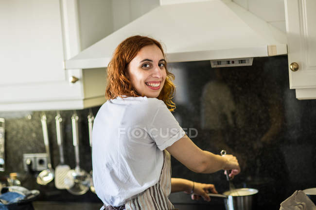 Улыбающаяся женщина готовит дома — стоковое фото