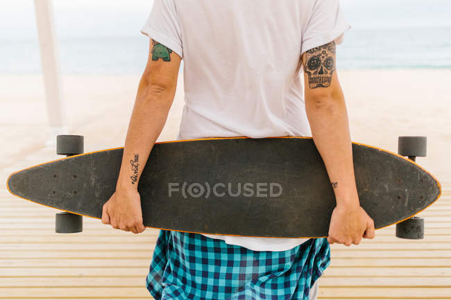 Татуированный человек держит скейтборд — стоковое фото