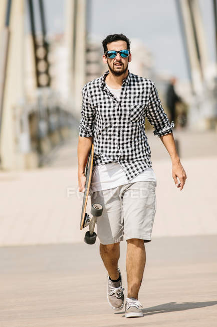 Homme marchant avec longboard — Photo de stock